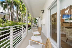 Un balcon avec des balustrades blanches, une petite table avec une plante et une chaise.