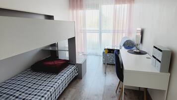 A compact room with a bunk bed, a desk, and a chair.