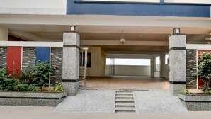 Una entrada moderna de edificio con escaleras, pilares de piedra y vista al interior.