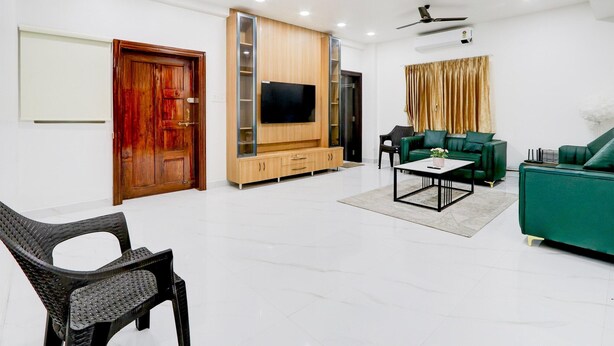Una sala de estar moderna con un televisor de pantalla plana, sofás verdes, una mesa de centro y un mueble de madera para entretenimiento.