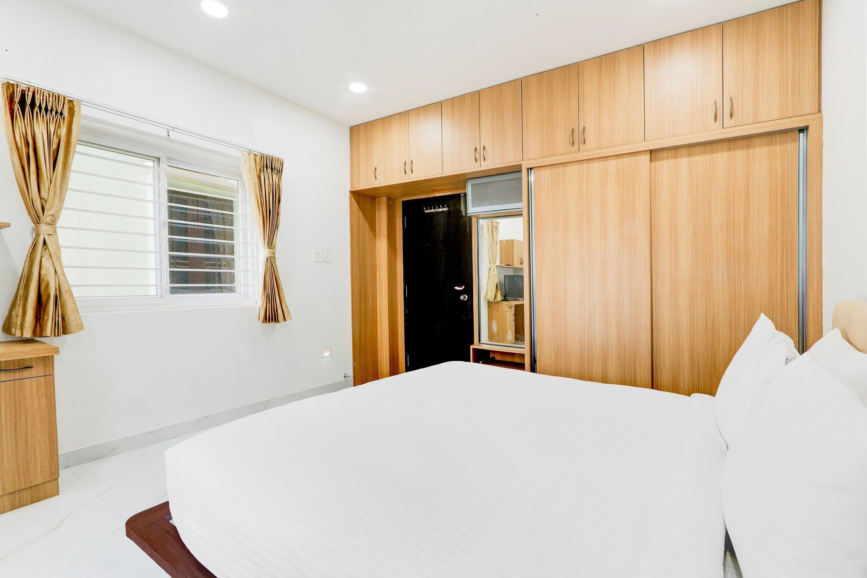 A bedroom with a bed, wooden wardrobe, and a window with curtains.