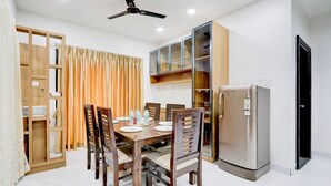 Un comedor con una mesa de madera, sillas, ventilador de techo y refrigerador.