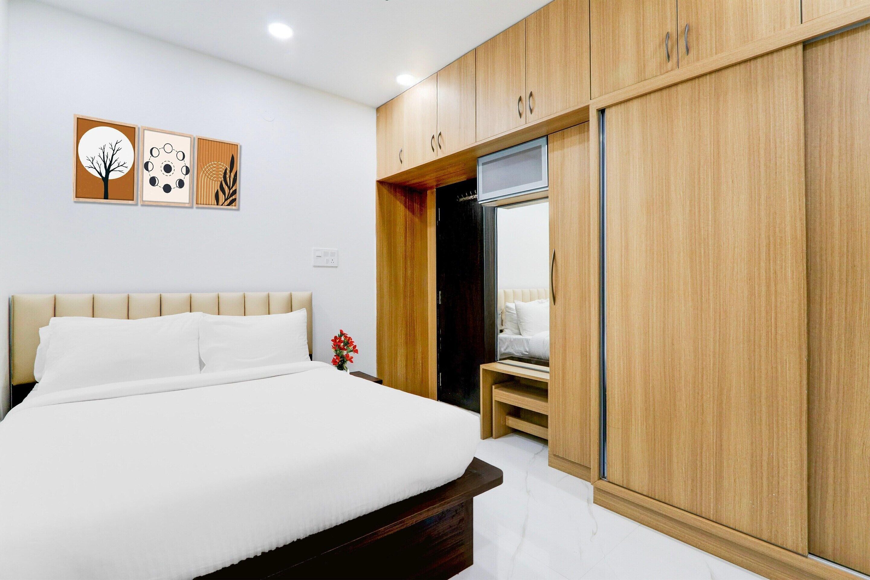 A bedroom with a bed, wooden wardrobe, and wall art.
