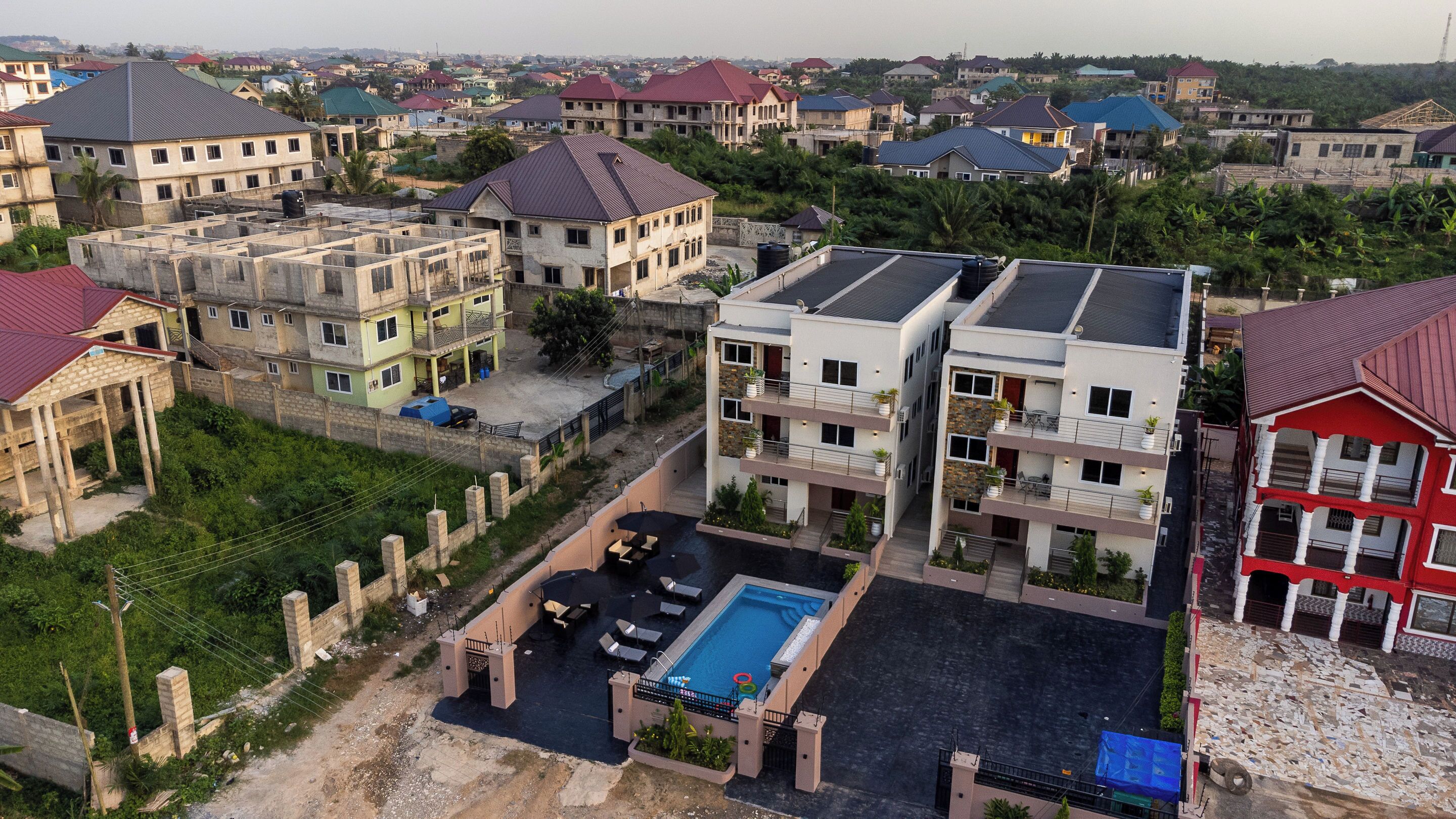 A residential area with multiple two-story houses, a swimming pool, and a gated entrance.