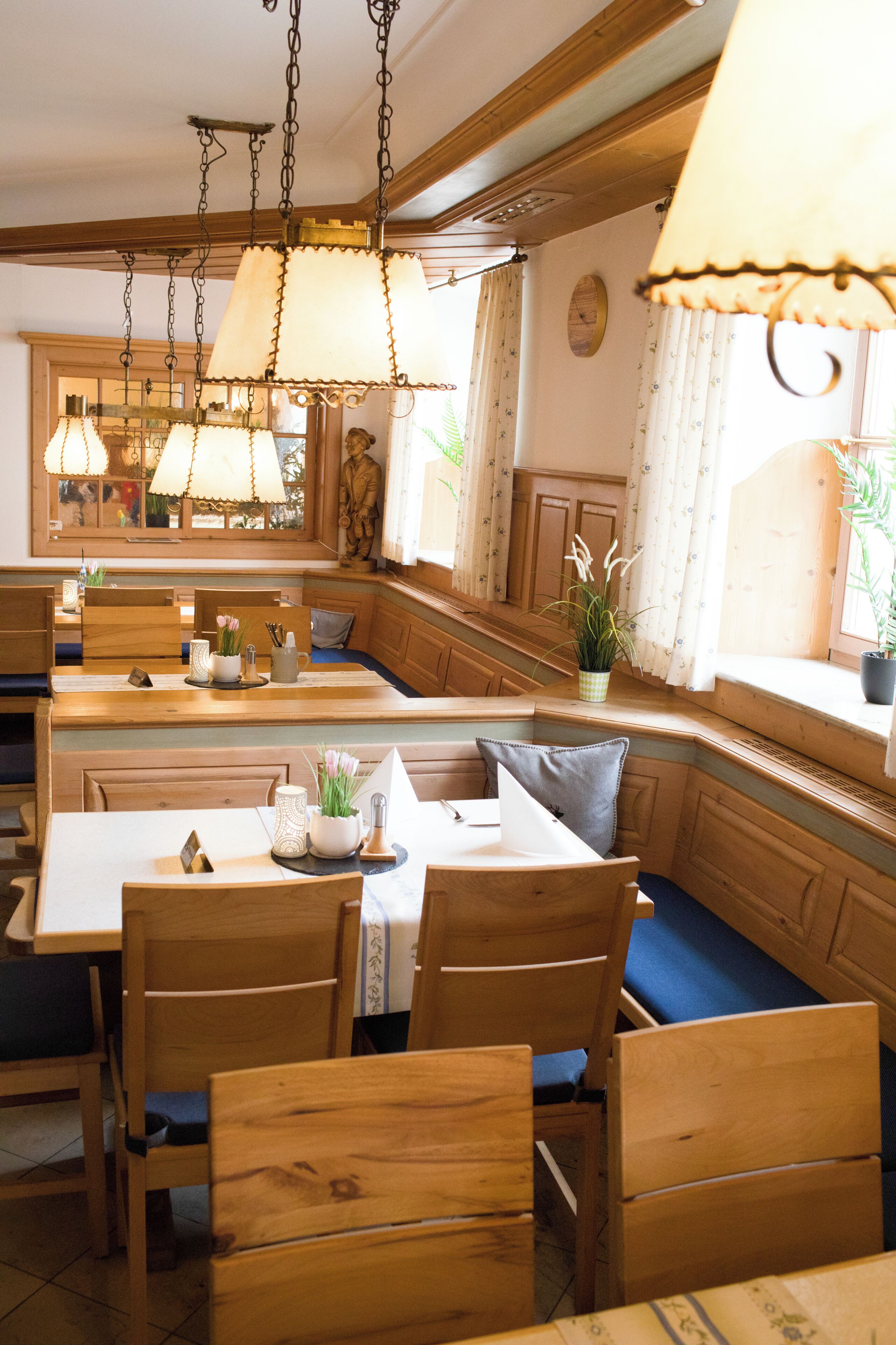 Un restaurante con mobiliario de madera, incluyendo cabinas y mesas, y lámparas colgantes.