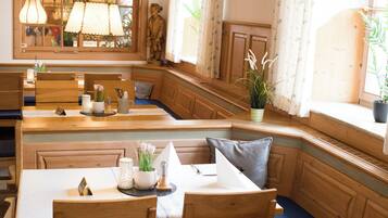 Un restaurante con mobiliario de madera, incluyendo cabinas y mesas, y lámparas colgantes.
