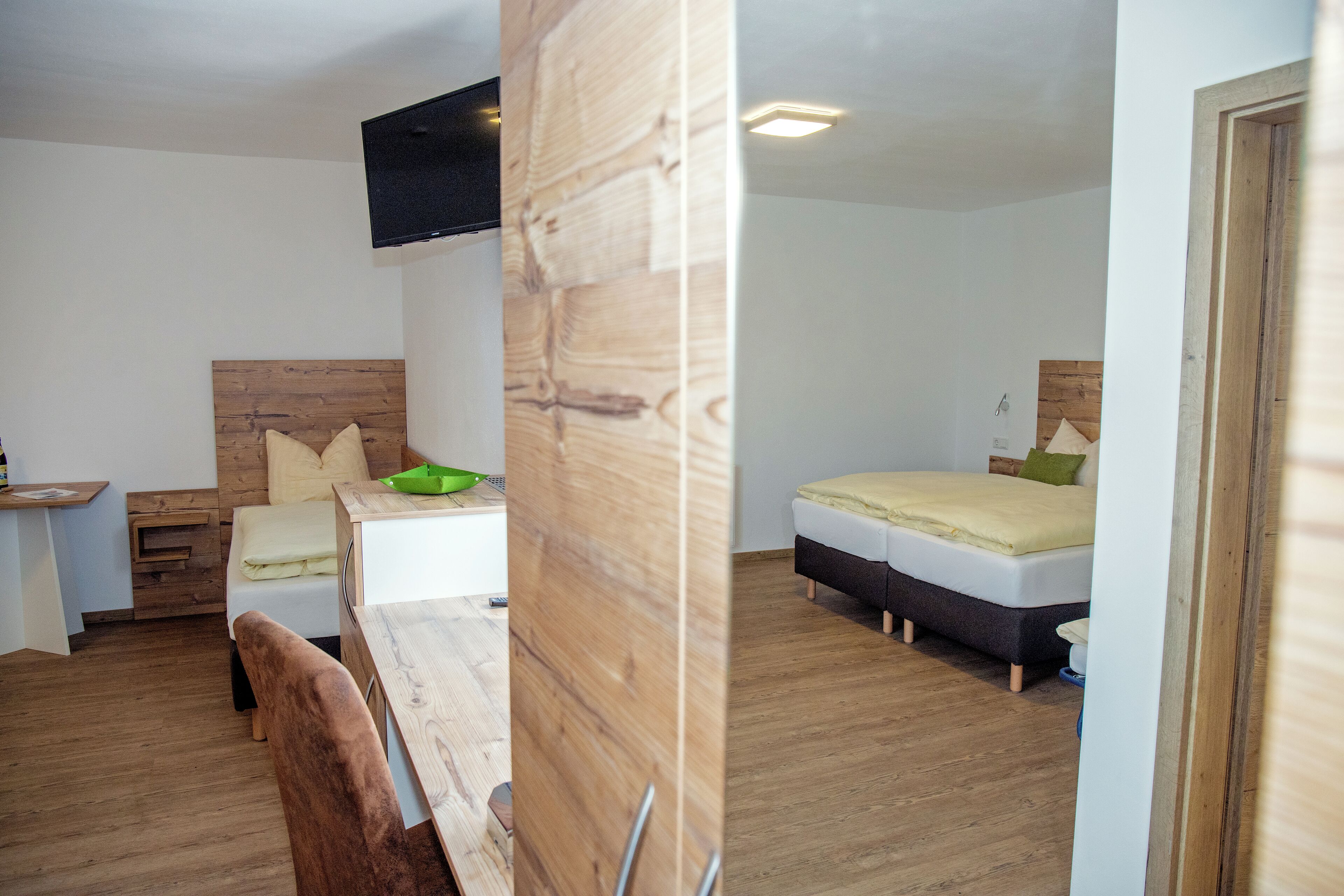 A compact room with a wooden headboard bed, a small desk, and a chair.