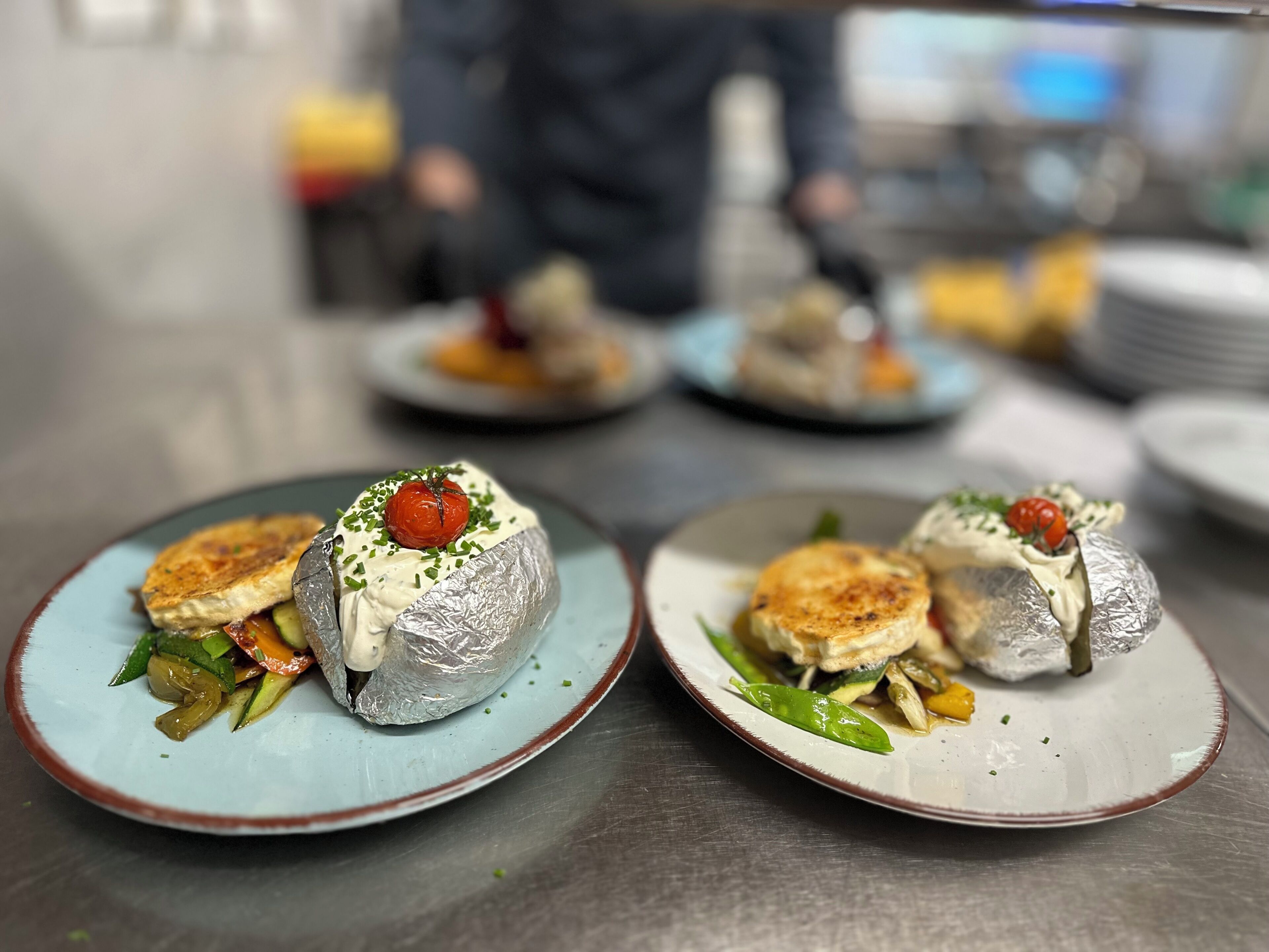 Una mesa de comedor con platos de comida, incluyendo un guiso con tomate y verduras.