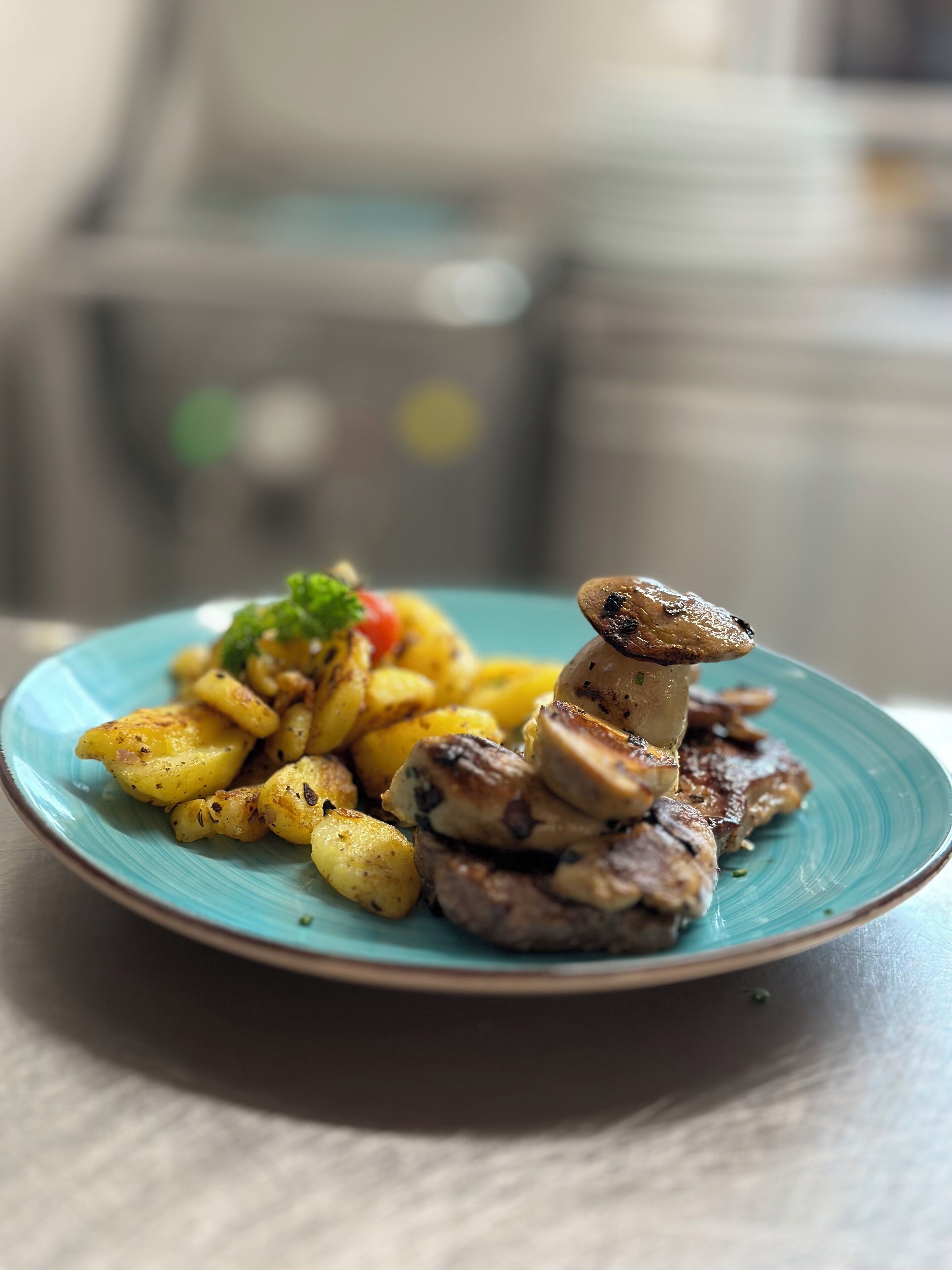 Un plato de papas y champiñones asados sobre un plato azul.