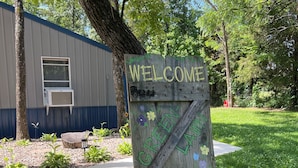A wooden welcome sign with 'WELCOME' and 'GETAWAY' painted on it, surrounded by a flower bed.
