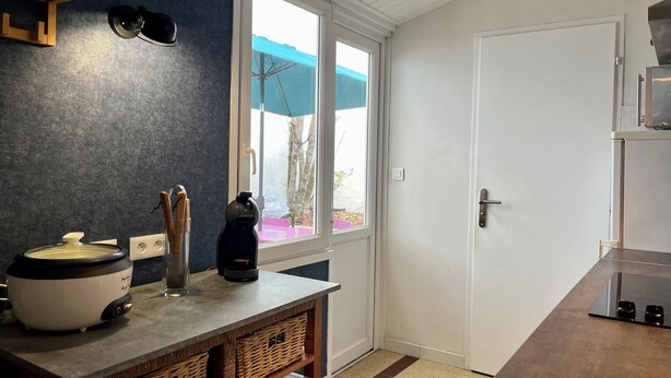 A modern kitchen with a stone countertop, a coffee maker, and a kettle. There is a window with a view of the outside.