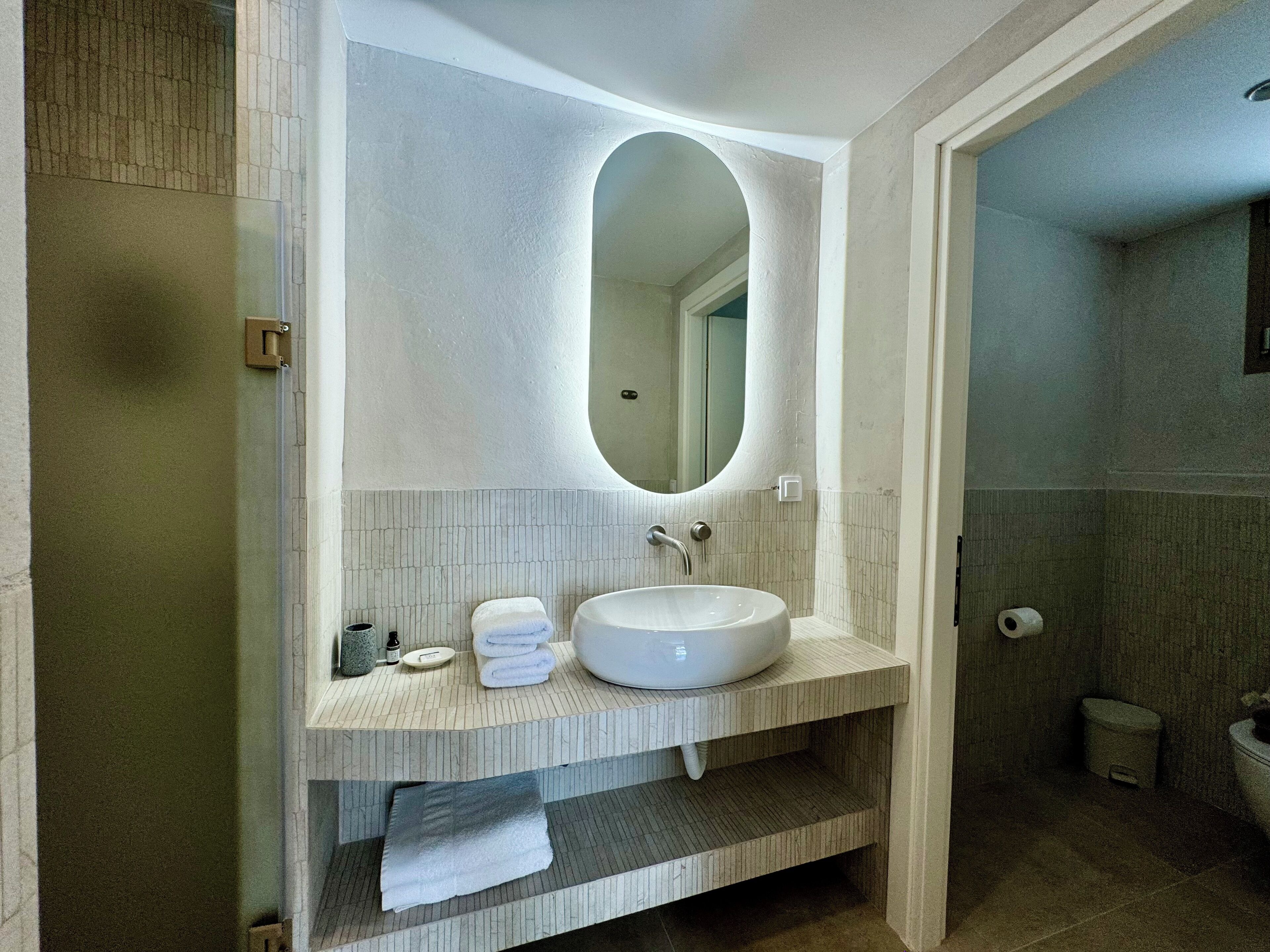 Un baño con un lavabo blanco, un espejo grande y un perchero para toallas.