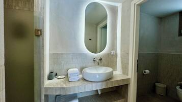 Une salle de bain avec un lavabo blanc, un grand miroir et un porte-serviettes.