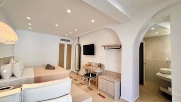 Un dormitorio moderno con cama, mesita de noche, televisor, armario y baño con lavabo y espejo.