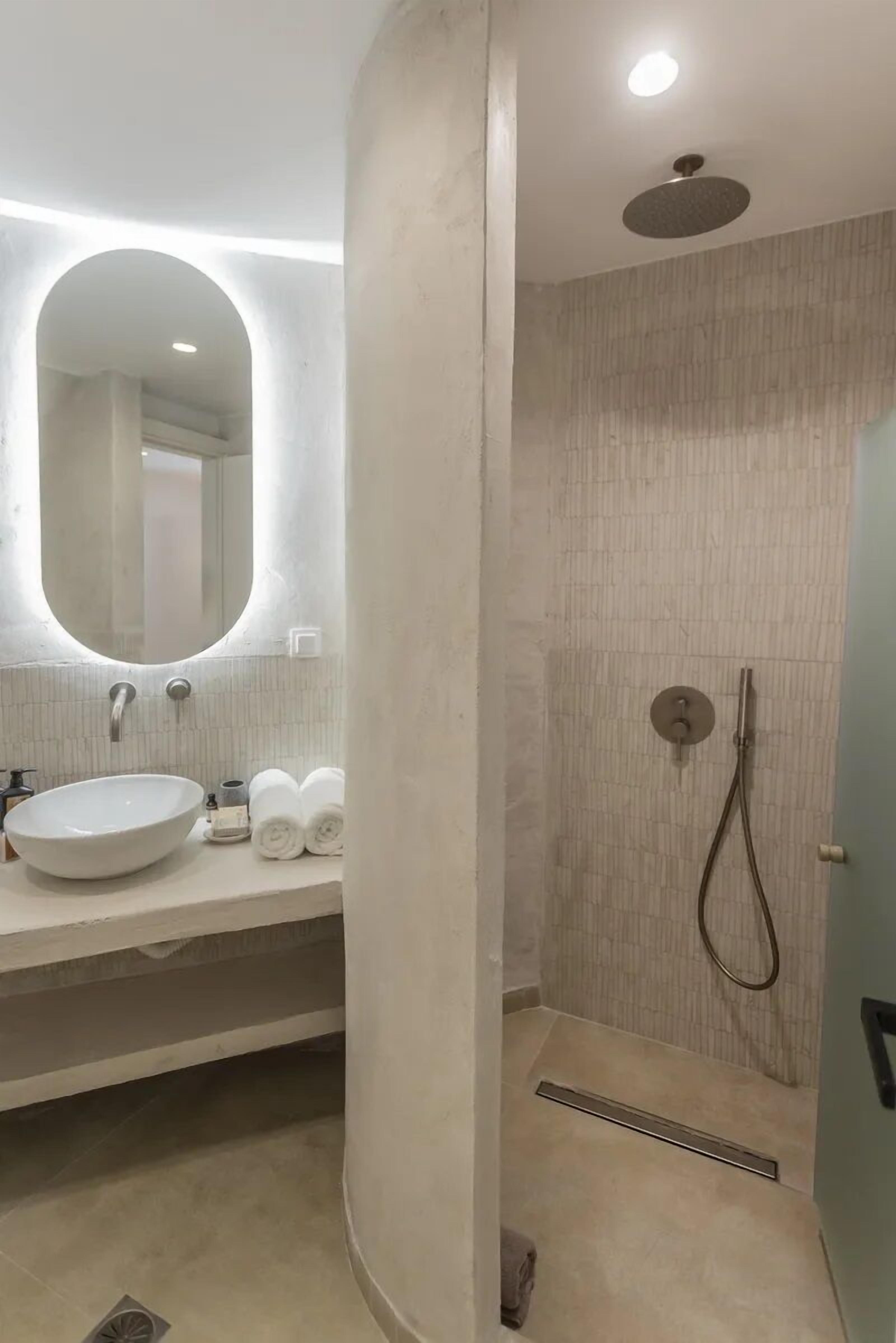 A modern bathroom with a round mirror, a sink, and a shower area.