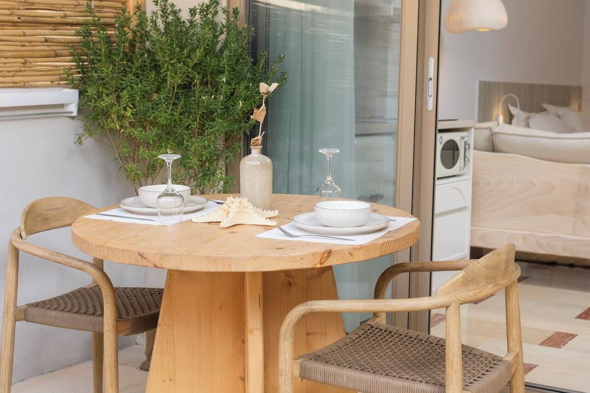 Un tavolo rotondo in legno con quattro sedie, una pianta in vaso e un candelabro.