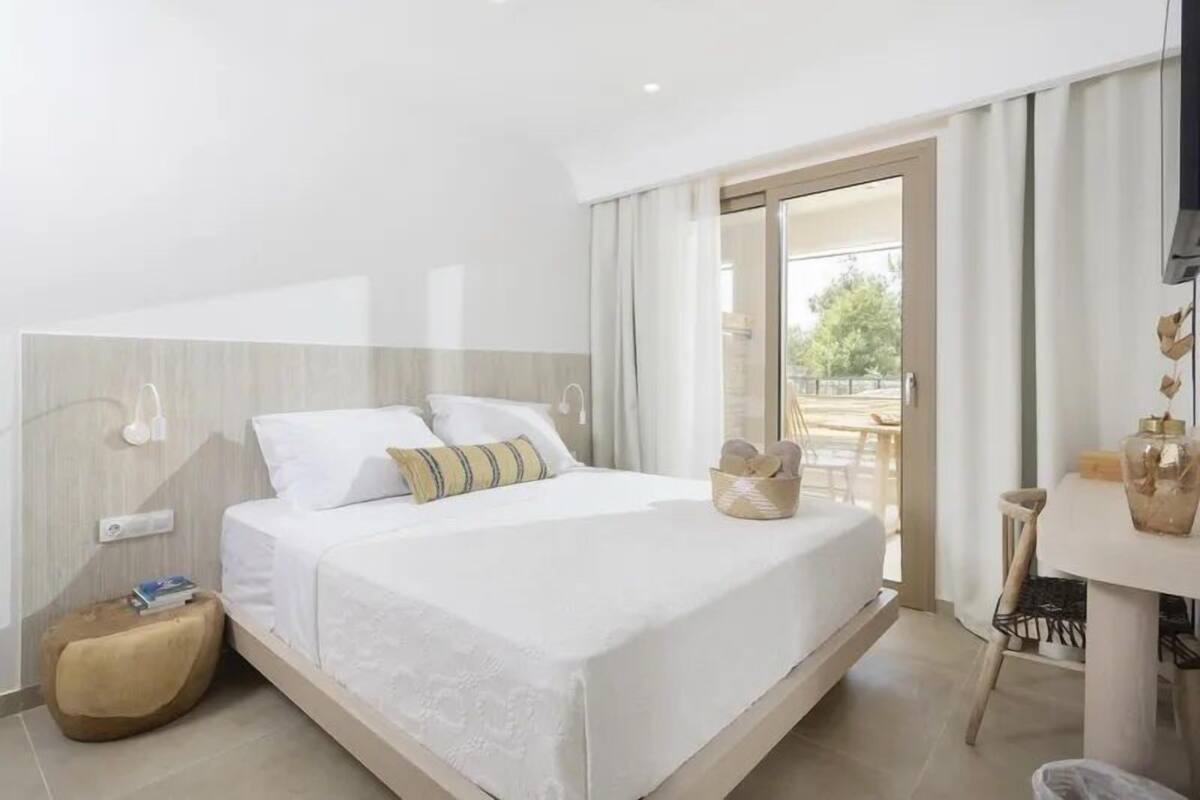 Una moderna camera d'albergo con un letto grande, un tavolino rotondo e vista sull'esterno.