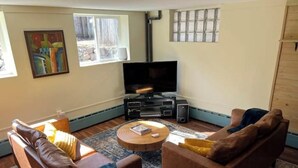 Ett vardagsrum med en platt-TV, två soffor, ett soffbord och en mönstrad matta.