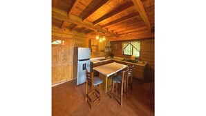 Una cucina in stile rustico con travi in legno, un frigorifero, un lavello e un'area pranzo con sgabelli.