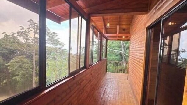 Un corridoio in legno con ampie finestre e un lampadario.