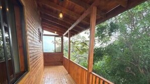 Un terrazzino in legno con ringhiera, vista sul verde e una finestra.