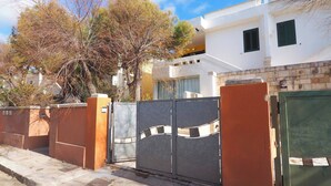 Una zona residencial privada con un edificio blanco, un muro marrón y una verja de metal.