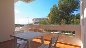 Un balcón con mesa y sillas, con vistas a una zona residencial con árboles y edificios.