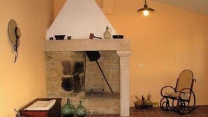 Una habitación con chimenea de piedra, un banco de madera y una lámpara colgante.