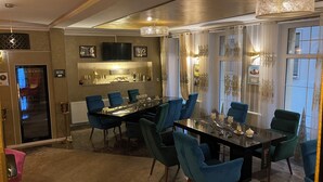 Uma sala de jantar com uma mesa comprida, cadeiras azuis e um candelabro.