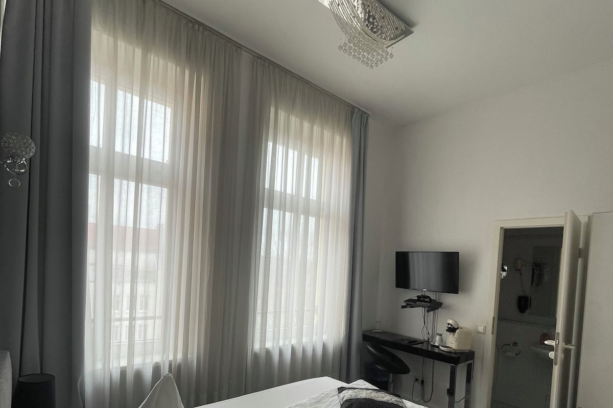 Ein Hotelzimmer mit Bett, Schreibtisch, Stuhl, Fernseher und einer Badezimmertür.