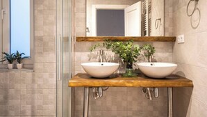 A bathroom with two sinks, a glass shower enclosure, and a wooden countertop. - Confort y Estilo en el Centro de Santander (Santander)