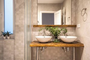 Ein Badezimmer mit zwei Waschbecken, einer Duschkabine aus Glas und einer Holztresenplatte.