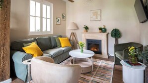 A living room with a fireplace, a sofa, a coffee table, and a television. - Confort y Estilo en el Centro de Santander (Santander)