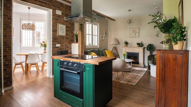 A modern kitchen with a green stove, a wooden island, and a brick wall. - Confort y Estilo en el Centro de Santander (Santander)