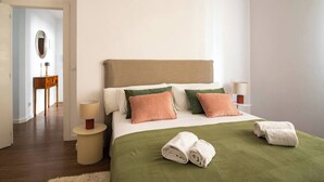 A hotel room with a bed, pillows, a bedside table, a lamp, a mirror, and a green blanket. - Confort y Estilo en el Centro de Santander (Santander)