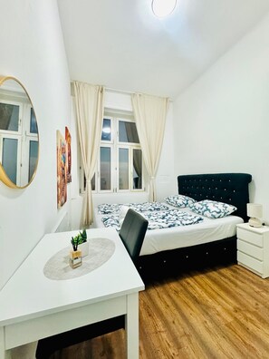 Une chambre à coucher avec un lit, une table de chevet et un bureau.