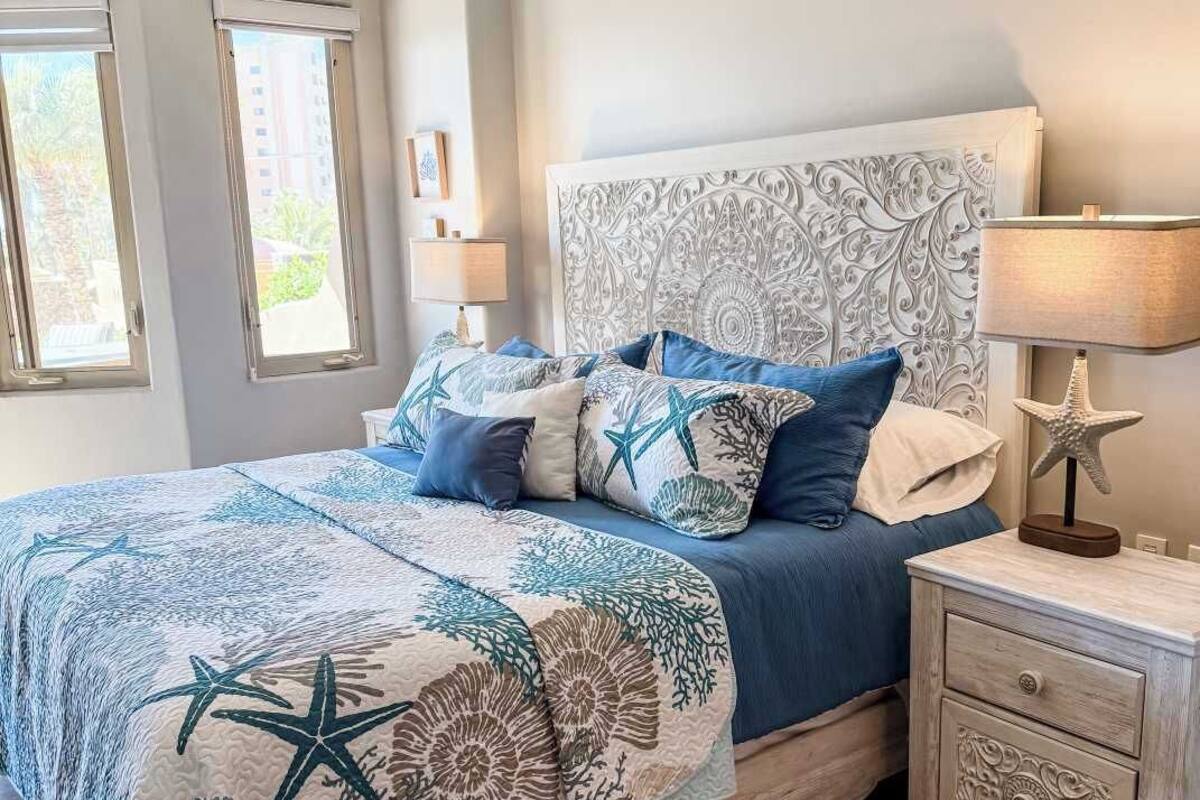 A bedroom with a bed, nightstands, a ceiling fan, and a window with blinds.