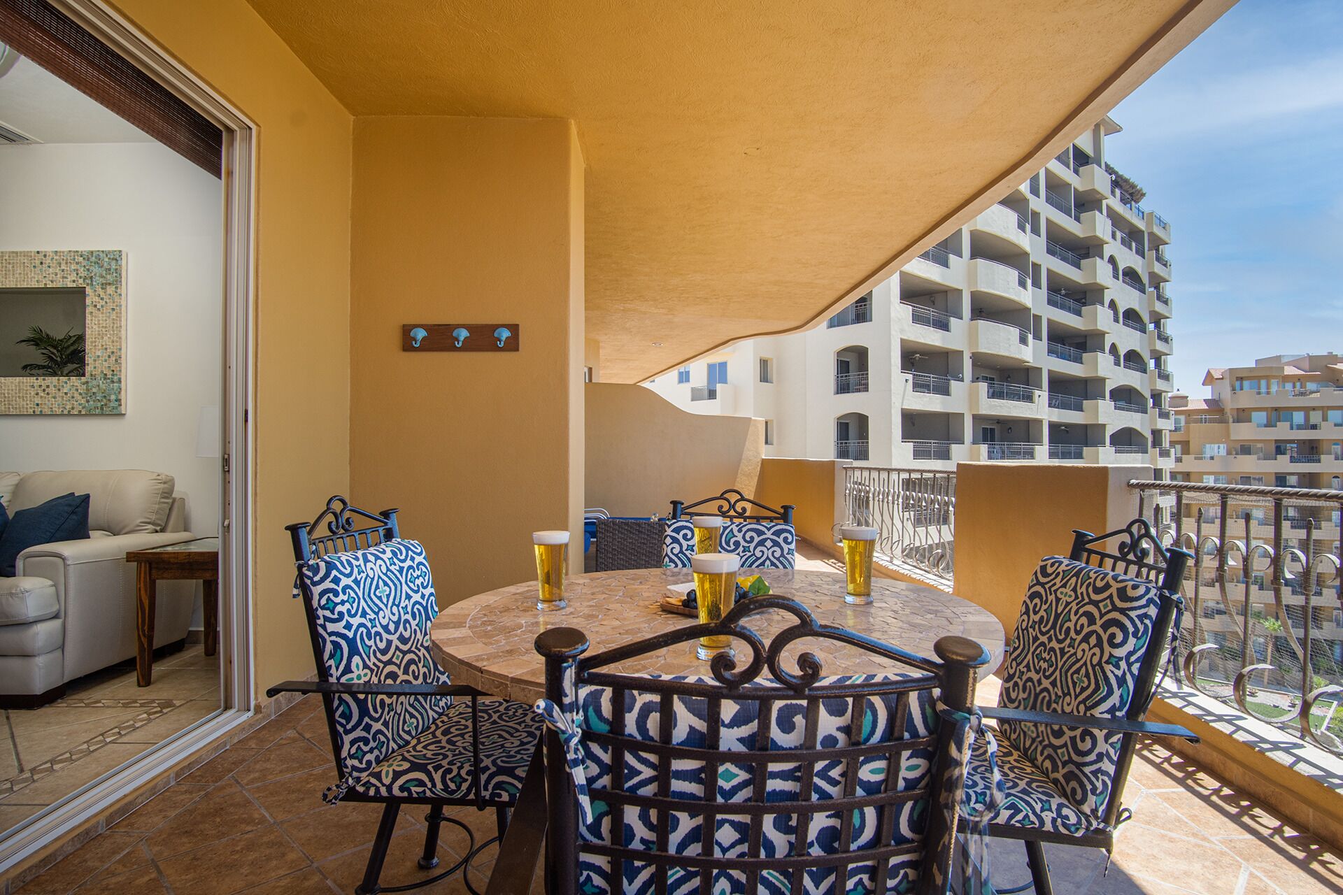 A balcony with a round table and chairs, a sofa, and a view of a multi-story building.