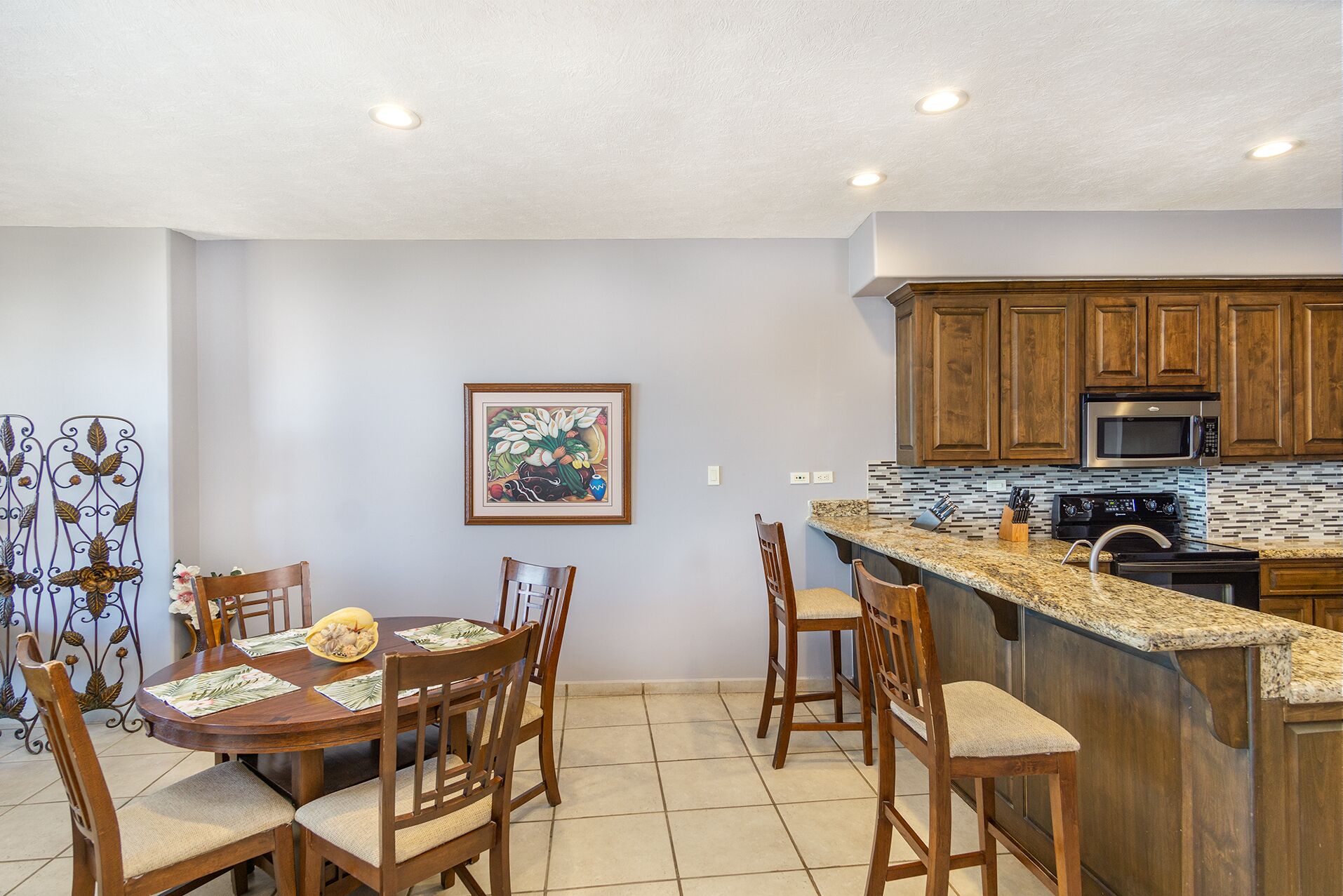 A kitchen with wooden cabinets, a granite countertop, and a stainless steel oven.