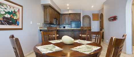 A dining area with a round wooden table, six chairs, and a central white vase.