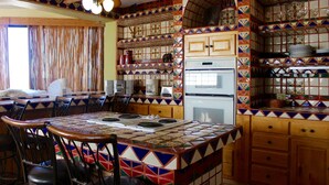 Una cocina con salpicadero de azulejos, armarios de madera y un comedor con sillas y una mesa.