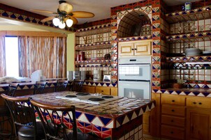 A kitchen with a tiled backsplash, wooden cabinets, and a dining area with chairs and a table.