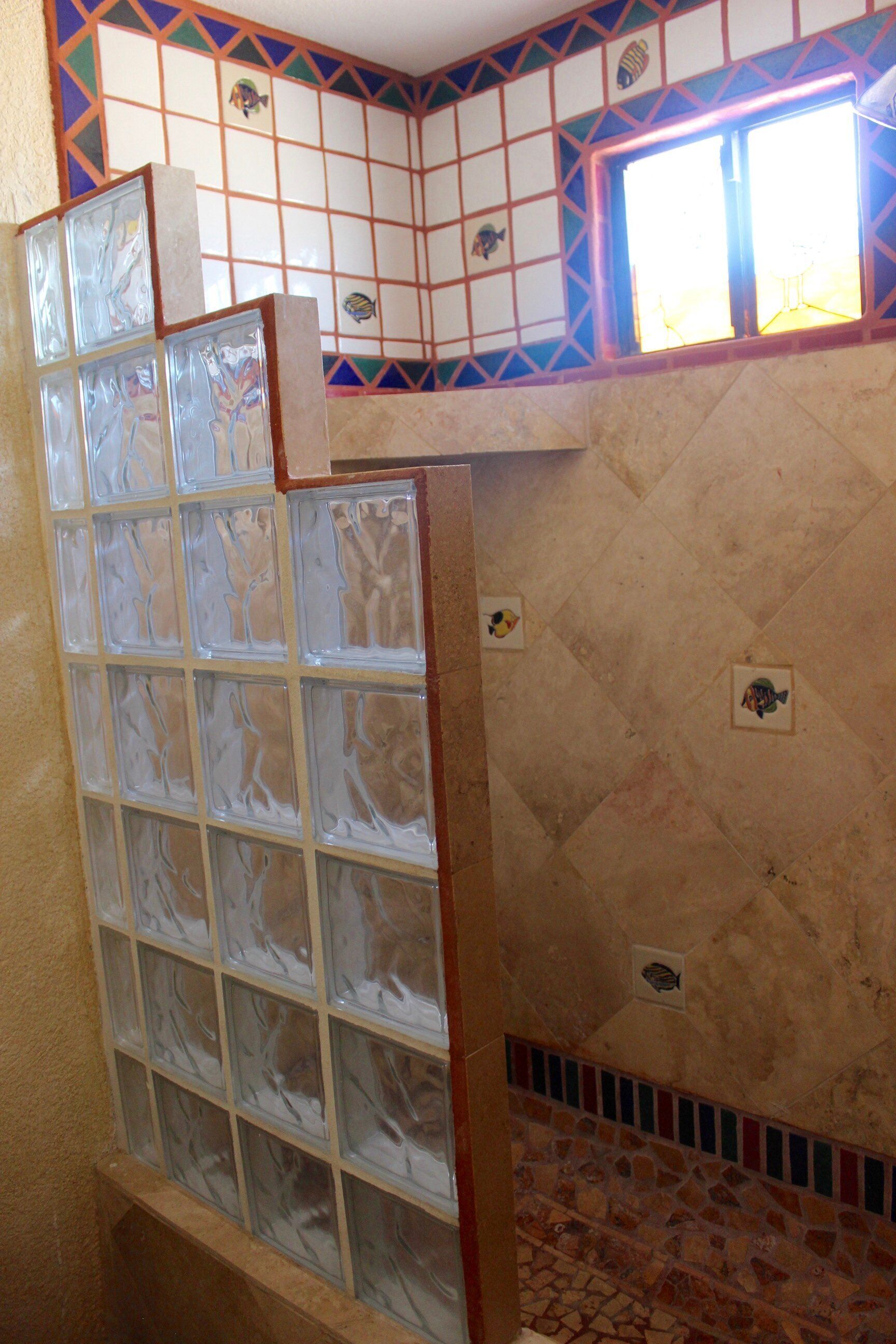 Une salle de bain avec un mur carrelé, une fenêtre et un sol carrelé.