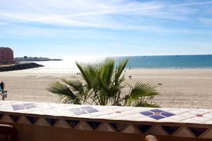 A beach view with a tiled patio in the foreground.