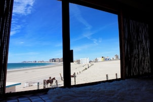 A beach view from inside a building with a large window.