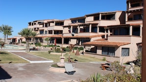 Un hotel de varios pisos con balcones, piscina y zonas de estar al aire libre.