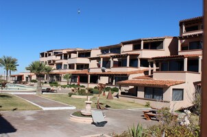 A multi-story hotel with balconies, a swimming pool, and outdoor seating areas.