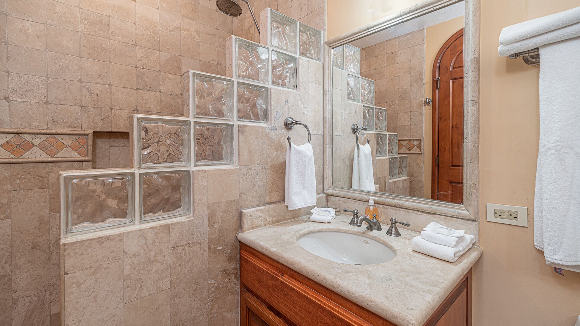 Un baño con un espejo grande, un lavamanos y una ducha.