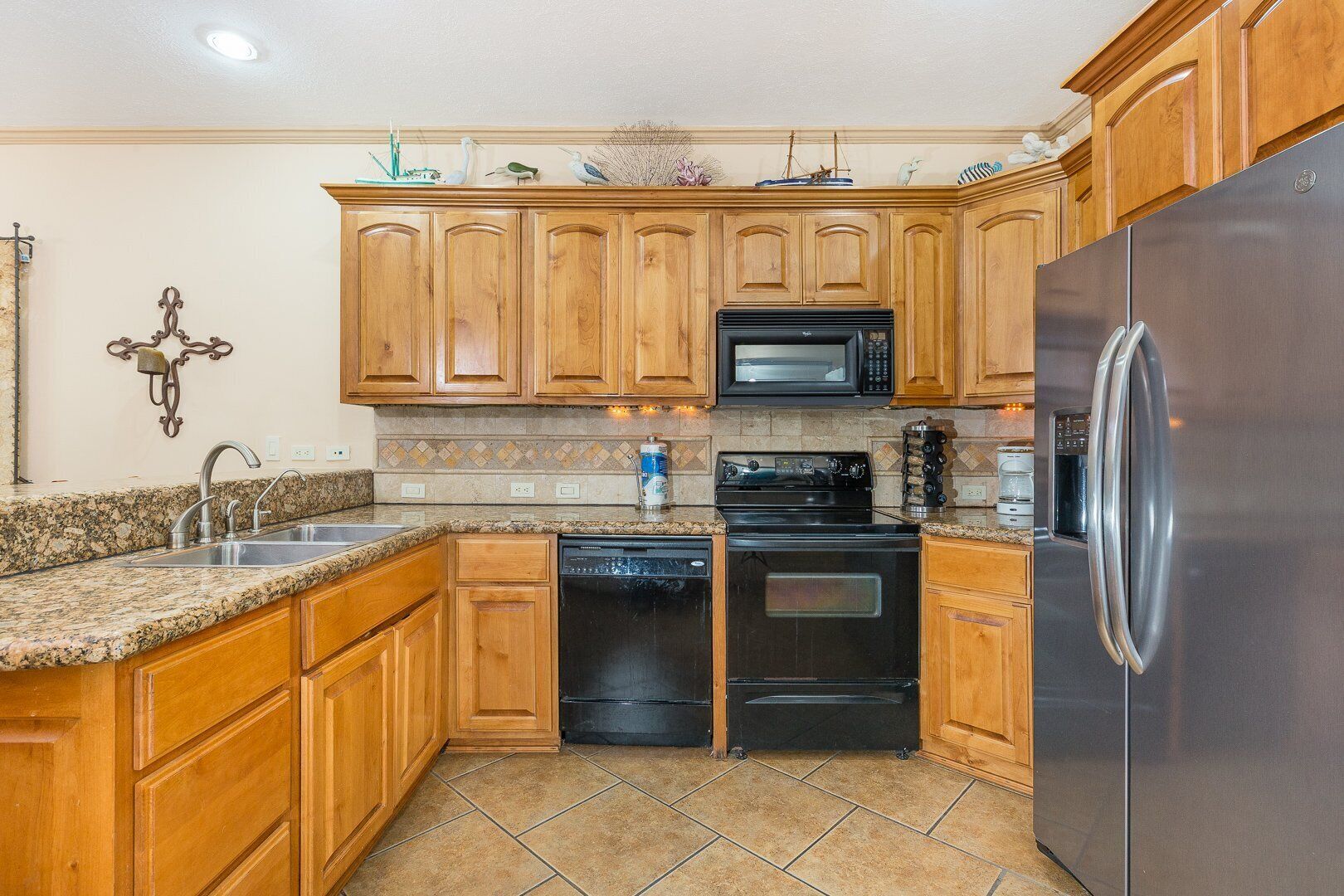 A kitchen with wooden cabinets, a stainless steel refrigerator, a microwave, a stove, and a dishwasher.