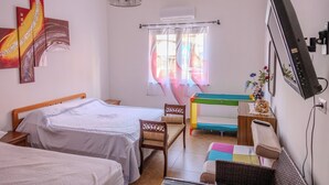 Een kamer met twee bedden, een bureau, een stoel, een televisie en een raam met gordijnen.